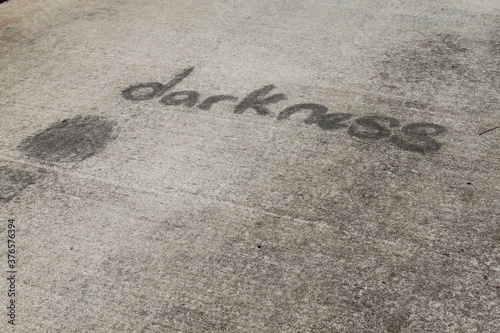 Cement pathway with darkness inscribed in black on it