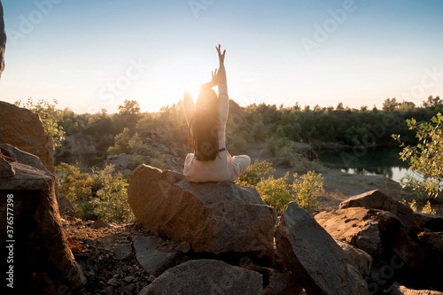 Beautiful brunette girl in a dress meditates at sunset in the mountains, climb the mountains.