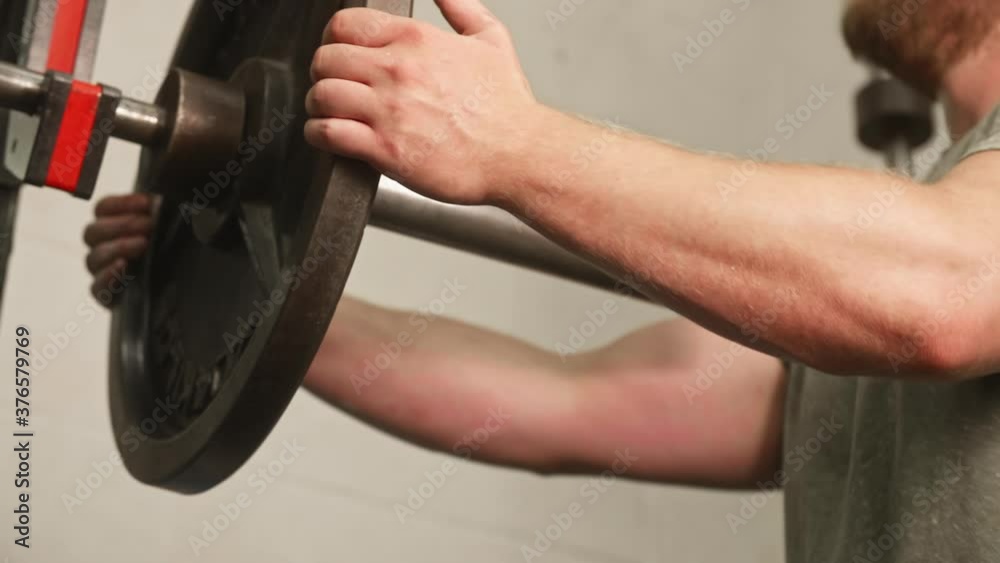 Man's hands sliding 45 pound weight plate off of barbell, Medium Shot, Low Angle, Slow Motion Man's hands sliding 45 pound weight plate off of barbell, Medium Shot, Low Angle, Slow Motion