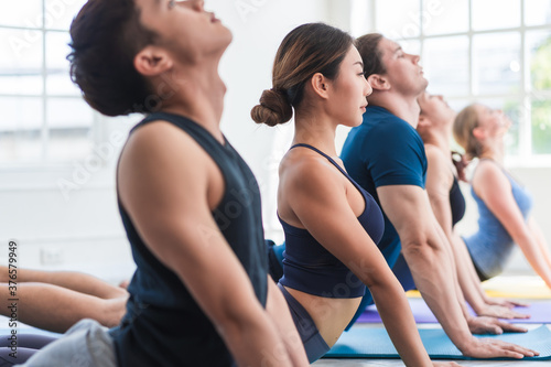 Multi ethnic group of people (Asian, Caucasian) in yoga class together