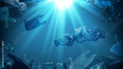 creative background of PET plastic bottles and single-use plastic bags floating in sea or ocean with rays of sunlight effect, polyethylene terephthalate plastic, concept of environmental pollution.