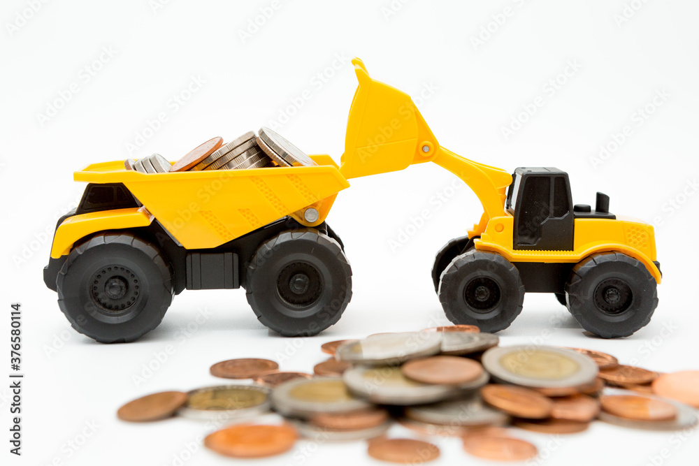 Model loader, Dump truck, coins stack on white background for money saving concept Model loader, Dump truck, coins stack on white background for money saving concept