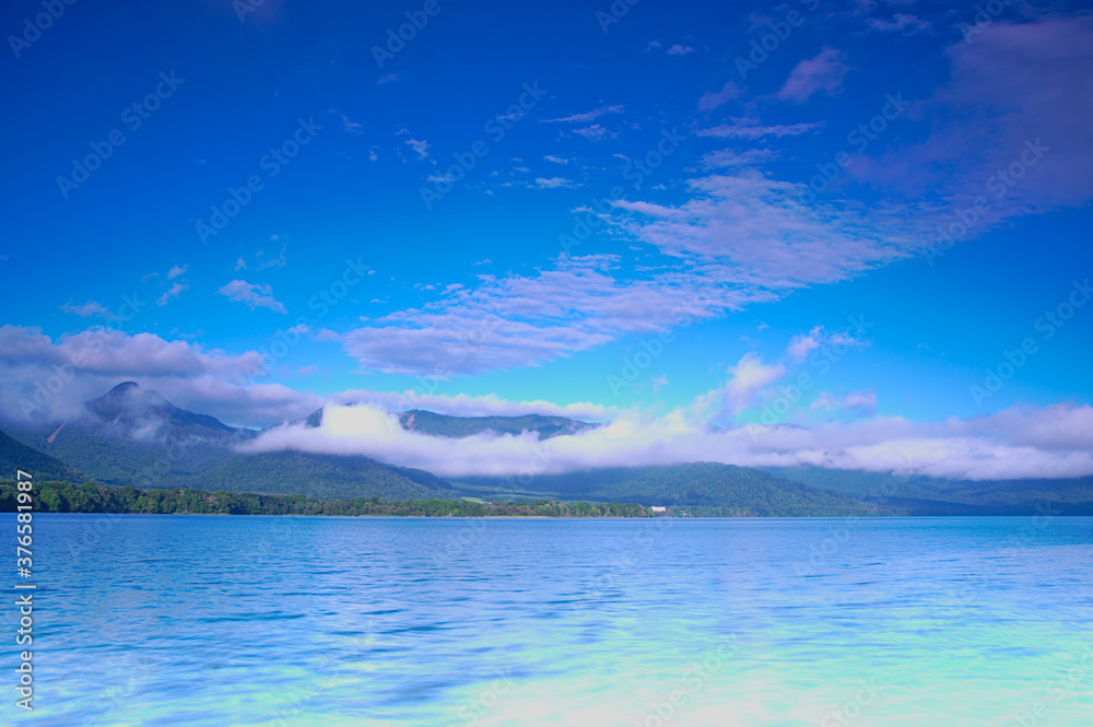 深い青空の下の湖。屈斜路湖、北海道。
Scenic landscape of mountain lake under deep blue sky. Lake Kussharo, Hokkaido, Japan.