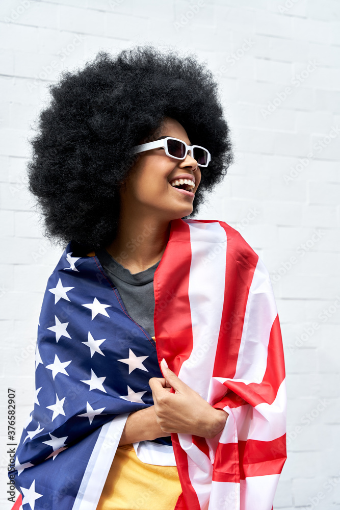 Happy young African American woman wrapped in USA flag laughing ...