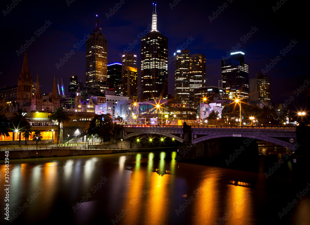 Melbourne Skyline with a reflection in the water of a couple standing on the bridge. Melbourne Skyline with a reflection in the water of a couple standing on the bridge.