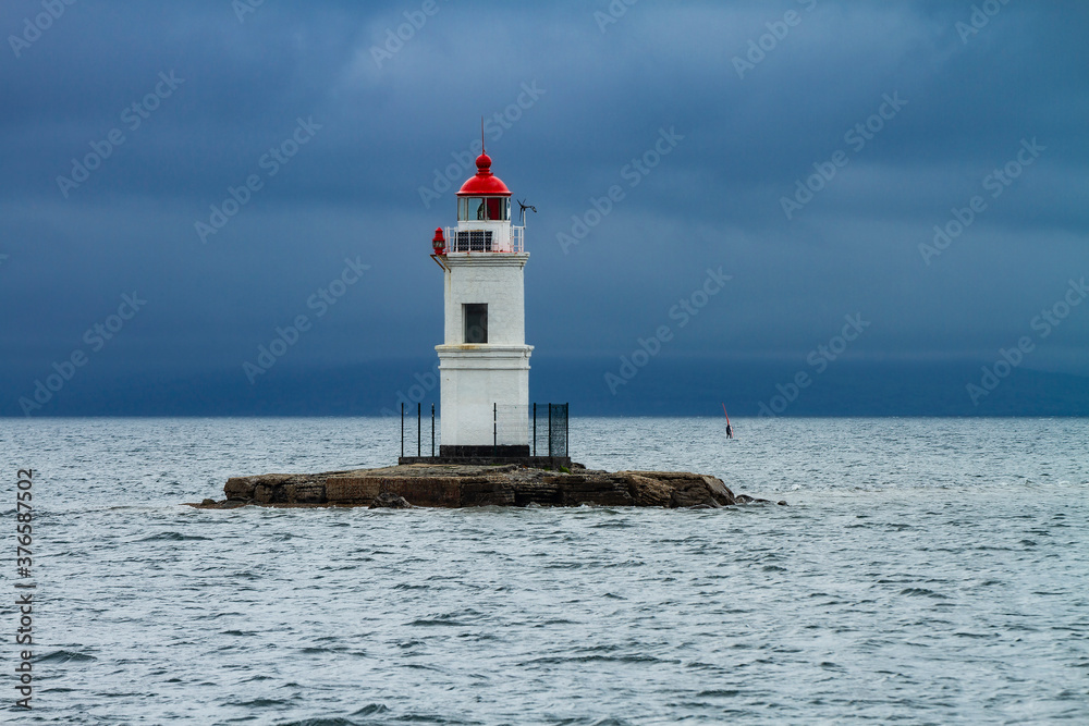 lighthouse on Cape Tokarevskaya cat in Vladivostok on the background of the sea in cloudy weather