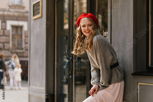 Cute young girl smiles warmly and looks away. Street portrait of a blonde in Paris. © Look!