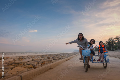 Fototapeta Naklejka Na Ścianę i Meble -  Asian families enjoy local tricycles on the beach on a nice day.