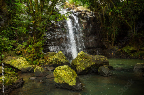 Waterfall landscape. Beautiful hidden waterfall in tropical rainforest. Foreground with big stones. Fast shutter speed. Sing Sing Angin waterfall  Bali  Indonesia