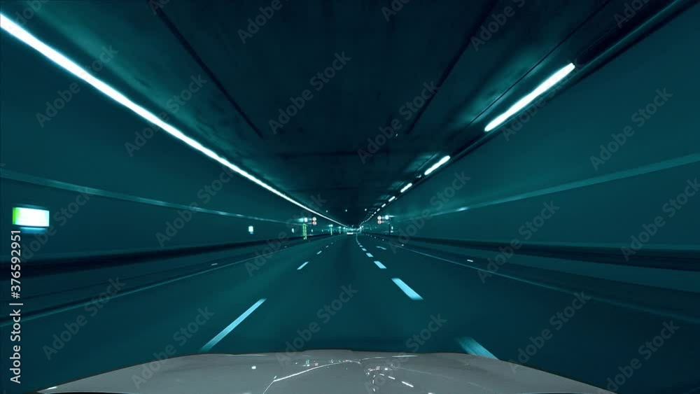 Fast drive by car through a tunnel in the Tenet movie / film look, with cyan, light bluish color tones. Following a car from the front window view with a speed ramp effect.