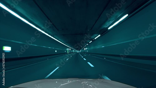 Fast drive by car through a tunnel in the Tenet movie / film look, with cyan, light bluish color tones. Following a car from the front window view with a speed ramp effect.