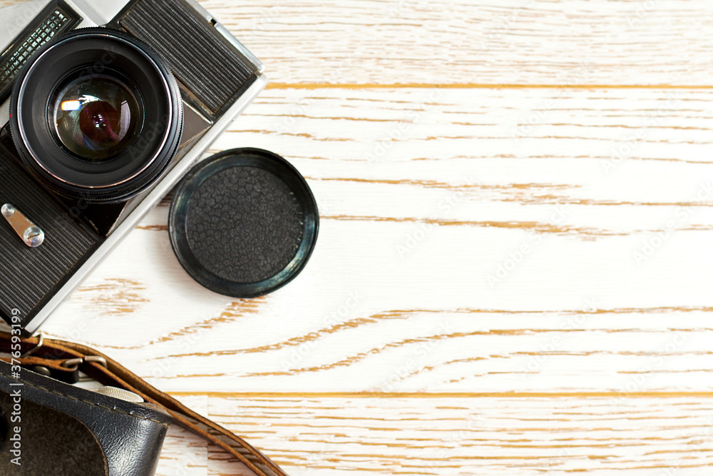 Old vintage camera with a leather case on the wooden surface. Backdrop