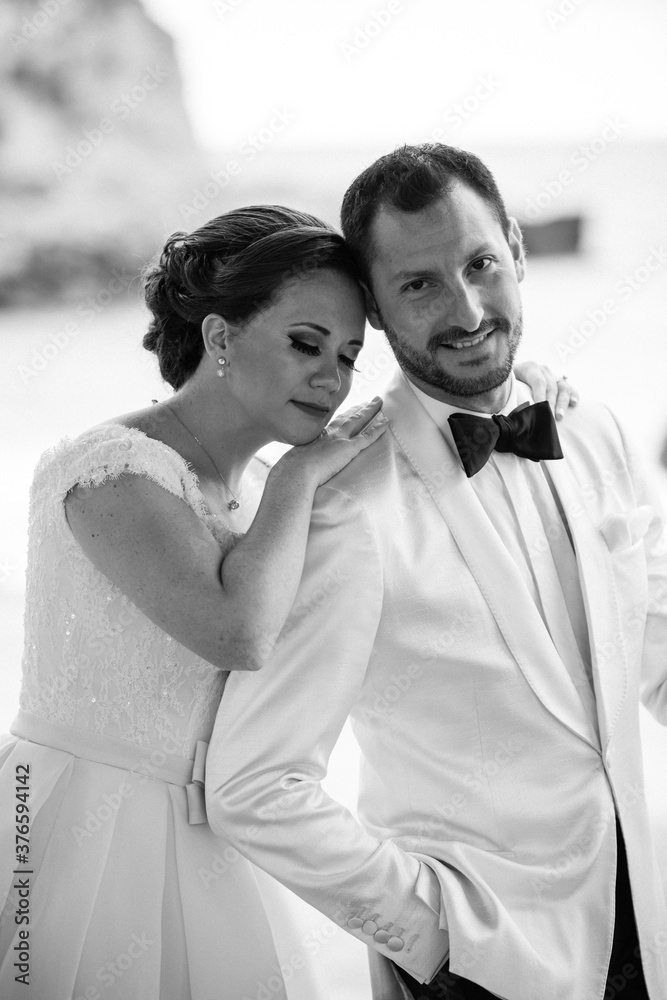 Latino Bride with eyes closed and groom with white tuxedo looking at the camera in black and white (close up) Latino Bride with eyes closed and groom with white tuxedo looking at the camera in black and white (close up)