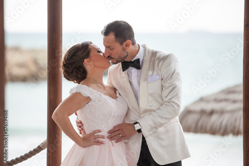 Latino Bride and groom with white tuxedo kissing (Close up)