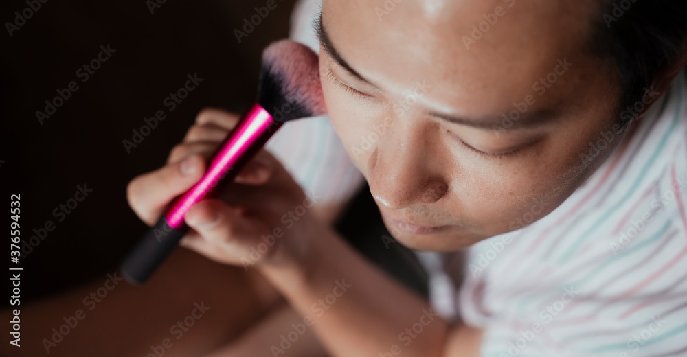 Asian gay brush his cheek with pink blush on.