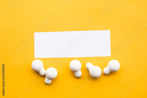 Business creativity and inspiration concepts with lightbulb and blank white paper on yellow background.