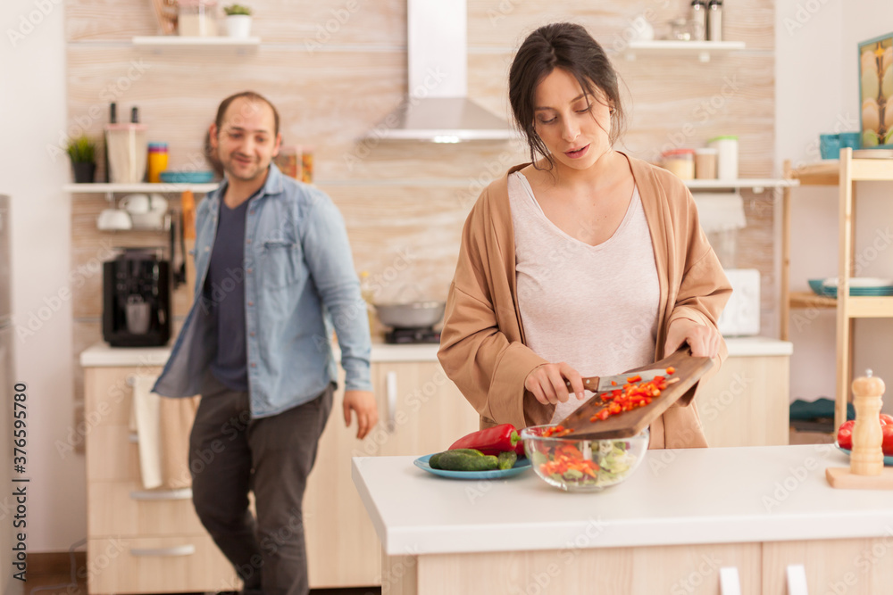 Wife making healthysalad in kitchen from fresh vegetables. Happy in love cheerful and carefree couple helping each other to prepare meal Wife making healthysalad in kitchen from fresh vegetables. Happy in love cheerful and carefree couple helping each other to prepare meal
