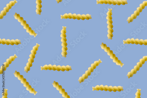 Fusilli pasta random flat lay on blue background without shadow. can be used as raw pasta background, poster, banner not pattern.