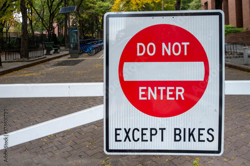  white red black street sign reading do not enter except bikes