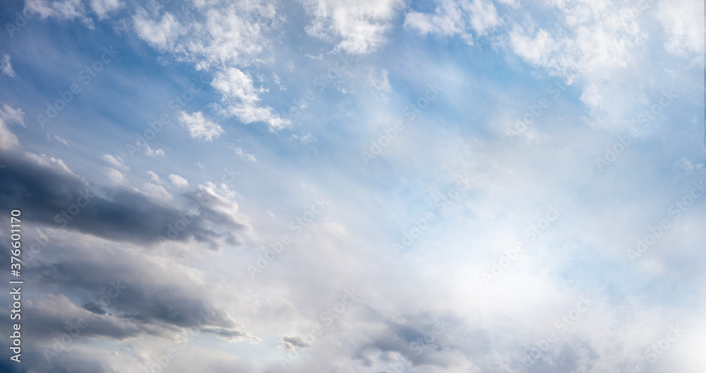 sunny light blue sky with white and dark clouds