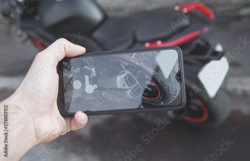 Man taking photo of a motorcycle on his phone.