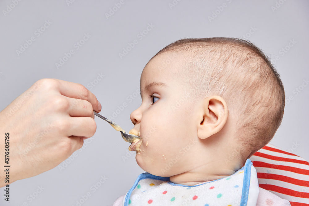 cute adorable baby eating porridge with a spoonful of the concept of proper nutrition cute adorable baby eating porridge with a spoonful of the concept of proper nutrition