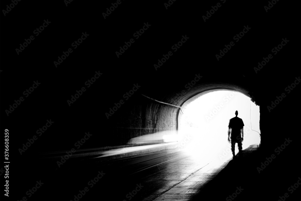 Moving silhouette of a young man in a dark tunnel in blur.