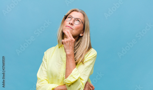 middle age pretty woman feeling thoughtful, wondering or imagining ideas, daydreaming and looking up to copy space