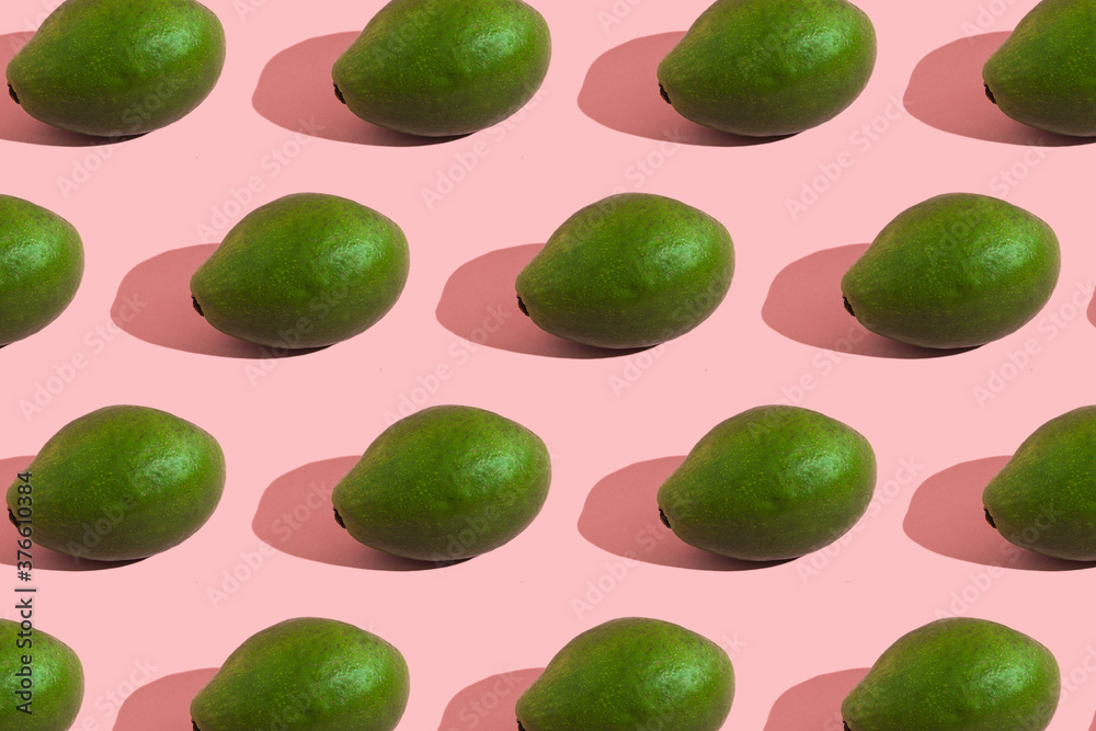 Trending style pattern of a whole green avocado on a pink background with hard light. Creative food texture. Trending style pattern of a whole green avocado on a pink background with hard light. Creative food texture.
