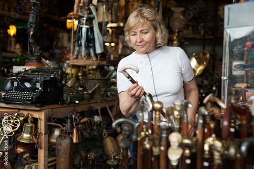Canvas Print Senior woman chooses rare walking stick at flea market