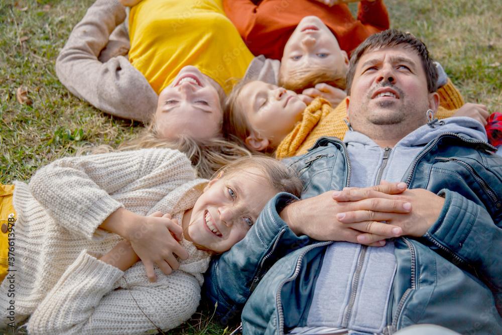 Family resting in the park at warm autumn weather. People wearing fall style clothes. Group of adults and kids are happy spending time together Family resting in the park at warm autumn weather. People wearing fall style clothes. Group of adults and kids are happy spending time together