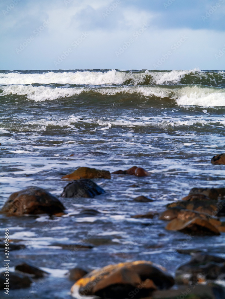Obraz premium Ocean waves in focus, foreground out of focus. Simple seascape, nobody, vertical image.