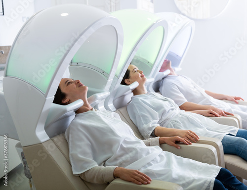 Portrait of clients resting in massage chairs for washing hair in salon