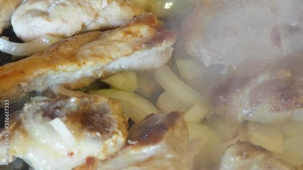 pork fried in oil with onions. Meat is frying. Hand touches pan. Grilled pork and chanterelles. How to cook savoury lunch.