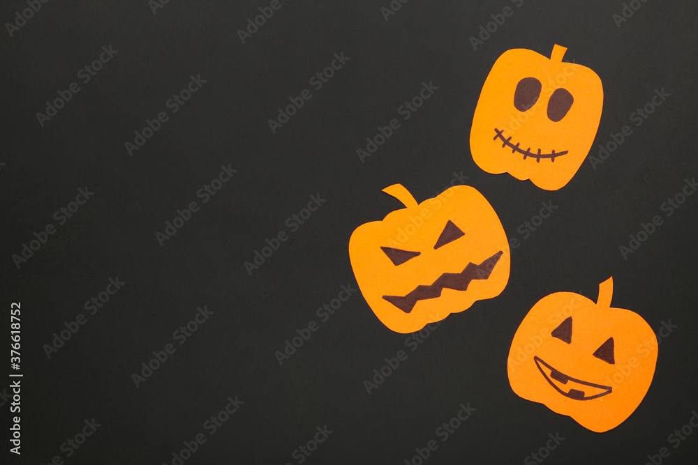 Halloween decorations with paper pumpkins on black background with copy space.