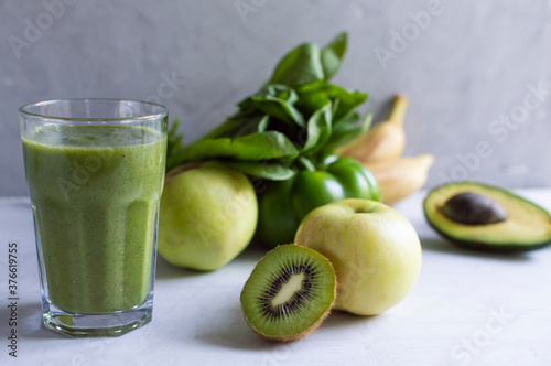 healthy fresh natural green smoothie in glass with bamboo juice straw. Made from spinach, apple, kiwi, avocado, bananas and pepper. Detox cocktail