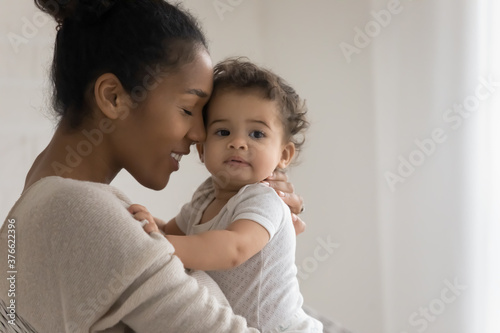 Bonding mixed race young mommy enjoying sweet tender moment with cute little toddler son or daughter at home, copy space for family relations parenting text, love care devotion maternity concept.