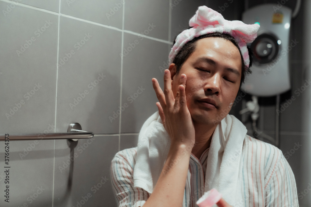 Asian gay apply facial cream in bathroom. Asian gay apply facial cream in bathroom.