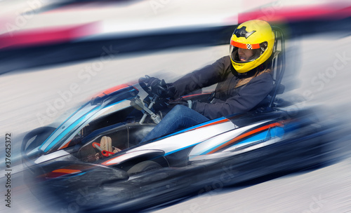 Young woman in helmet driving car for karting in sport club outdoor © JackF