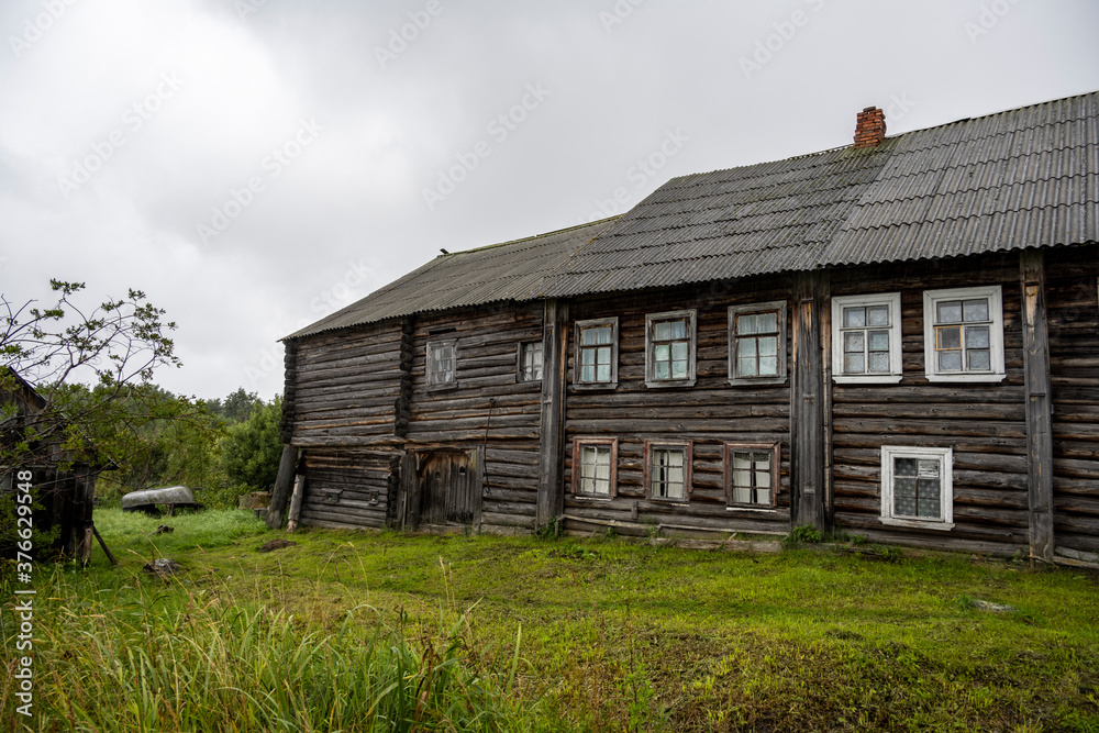 landscape with rustic wooden houses of a very old construction against the background of a gray northern sky landscape with rustic wooden houses of a very old construction against the background of a gray northern sky
