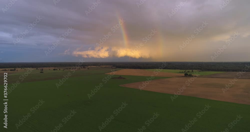 Aerial view of double rainbow and sunset clouds over agriculture farmland field