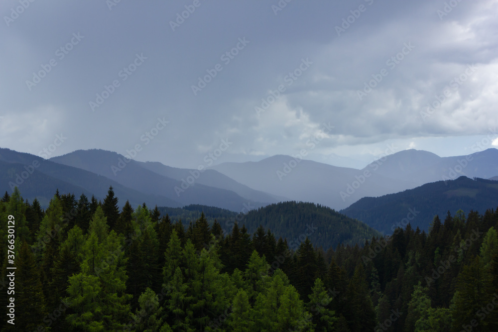 Mountain range in the Alps with local thunderstorm and rain shower in the distance