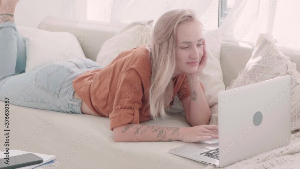 Blonde Woman Using Computer Laptop Lying Comfortable Sofa. Girl Relaxing On Couch Typing On Notebook. Girl Student Distance Learning. Millennial People Remote Education. Distance Job. Internet Surfing Blonde Woman Using Computer Laptop Lying Comfortable Sofa. Girl Relaxing On Couch Typing On Notebook. Girl Student Distance Learning. Millennial People Remote Education. Distance Job. Internet Surfing