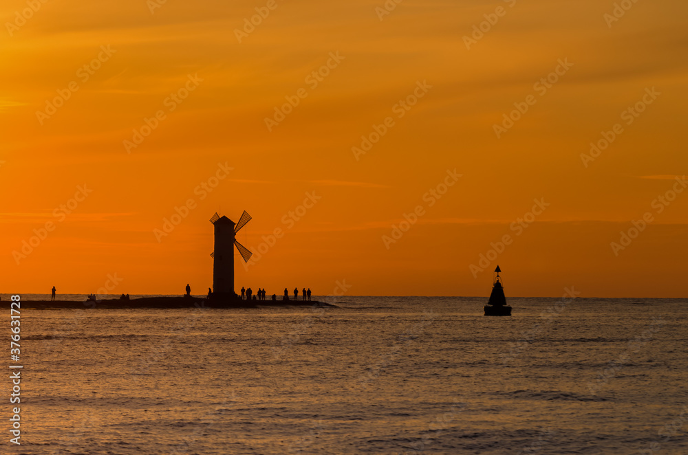 NAVIGATION SIGN ON THE BREAKWATER - Sunset on the seashore in Swinoujscie
