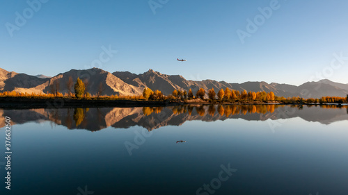A plane is flying over mountains and rivers at sunrise. 