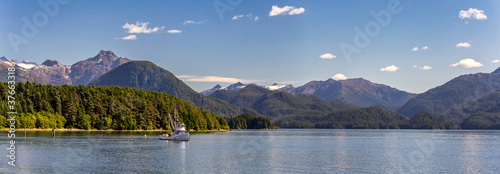 Photos A beautiful panoramic shot of a harbour in Sitka, AK with a commercial fishing boat anchored in it, green forest, mountains with snowy peaks, and gorgeous blue sky