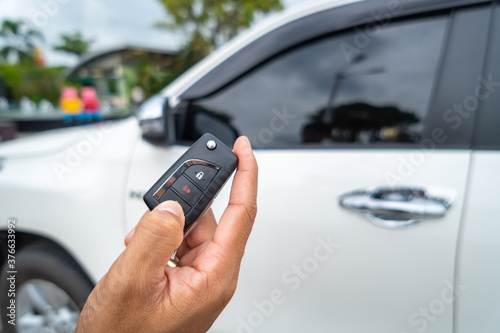 Hand pressing the button on the remote to lock or unlock the car with the remote control.