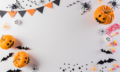 Halloween decorations made from pumpkin, paper bats and black spider on pastel orange background. Flat lay, top view with copy space for text.