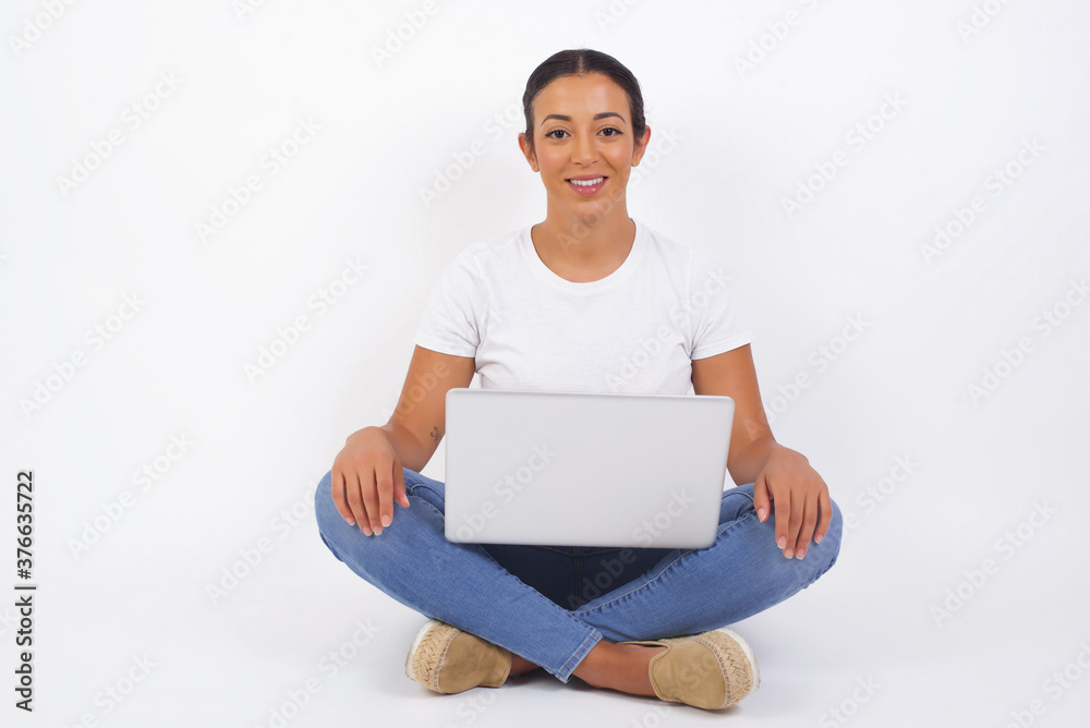 Confidence and business concept. Portrait of charming successful young girl, smiling broadly with self-assured expression while holding hands in pockets standing against gray wall. Confidence and business concept. Portrait of charming successful young girl, smiling broadly with self-assured expression while holding hands in pockets standing against gray wall.