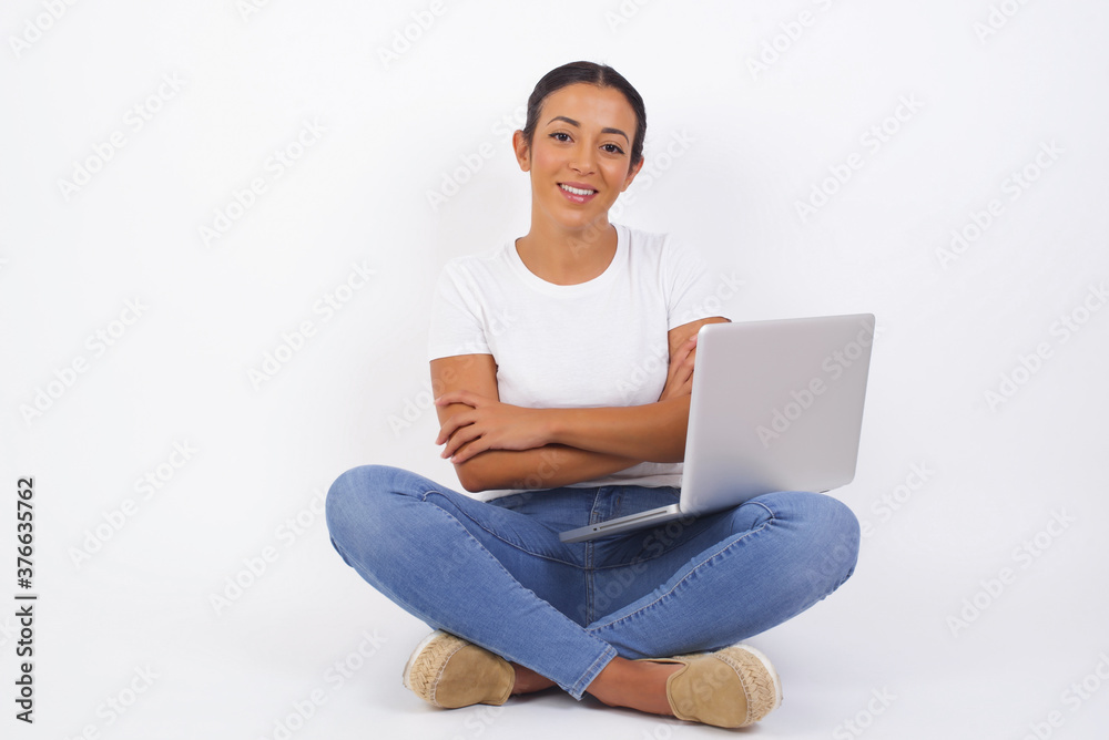 Brunette girl happy face smiling with crossed arms looking confident at the camera standing against gray wall. Positive person. Brunette girl happy face smiling with crossed arms looking confident at the camera standing against gray wall. Positive person.